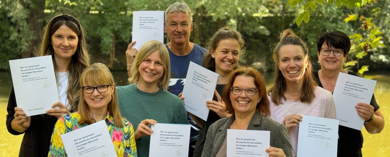 Das Team von Irrsinnig Menschlich e.V. hält den Jahresbericht 2023 hoch.
